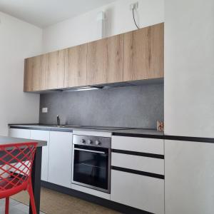 a kitchen with white and black appliances and a red chair at Ca' Massima, il cuore a Monza in Lissone