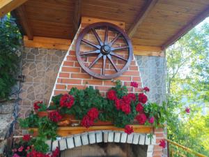 a brick wall with a wooden wagon wheel and flowers at Guest House Stoletnika in Yagodina
