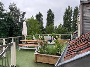 une terrasse avec une table, un banc et un parasol dans l'établissement B&B Het Eycken Huys, à Aalter