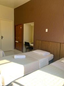 a hotel room with two beds and a desk at Hotel Ideal in Chapecó