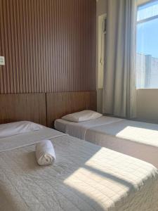 1 dormitorio con 2 camas, ventana y almohada en Hotel Ideal, en Chapecó
