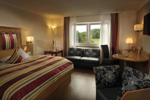 ein Hotelzimmer mit einem Bett, einer Couch und einem Fenster in der Unterkunft Landidyll Hotel Restaurant Birkenhof in Klosterkumbd