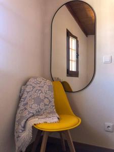 a yellow chair in a room with a mirror at Casa da Praça in Freixo de Numão