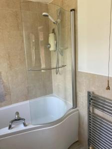 a bathroom with a bath tub with a shower at Cheerful 3 bedroom property set in the countryside in Westcott