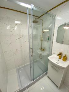 baño blanco con ducha y lavamanos en Apartament Panorama Centrum, en Legnica