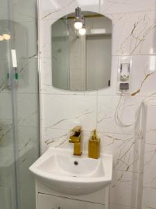 ein weißes Badezimmer mit einem Waschbecken und einem Spiegel in der Unterkunft Apartament Panorama Centrum in Legnica