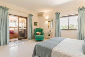 a bedroom with a bed and a green chair at Central Cascais Apartment with private parking in Cascais