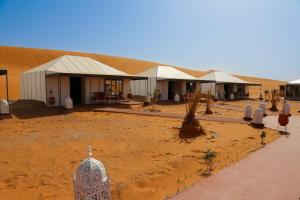 Merzouga Luxury Traditional Camp في مرزوقة: مجموعة من الخيام في الصحراء مع مبنى