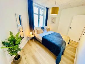a bedroom with a blue bed and a potted plant at aday - Frederikshavn apartment on the Pedestrian street in Frederikshavn
