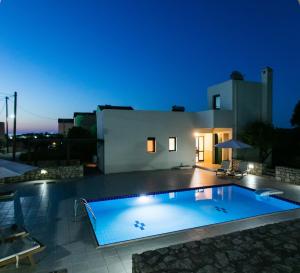 una piscina frente a una casa por la noche en Villa Athina en Asprouliánoi