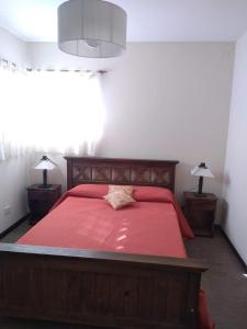een slaapkamer met een groot rood bed met 2 lampen bij EL BAGUAL DE MONTE in San Miguel del Monte