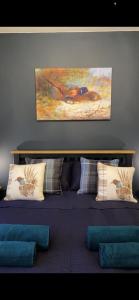 a bedroom with a bed with pillows and a painting on the wall at Haste Ye Back in Inverness