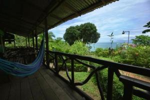 a hammock on a deck with a view of the ocean at Cabinas vista isla del caño corcovado in Drake