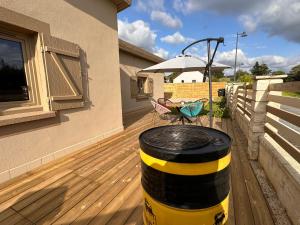 a barrel on a deck with a table and an umbrella at L’impasse - Au bord de l’eau in Épagne-Épagnette