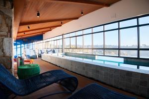 a swimming pool with blue chairs in a building with windows at Wanderlust in Campos do Jordão