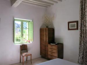 ein Schlafzimmer mit einer Kommode, einem Fenster und einem Stuhl in der Unterkunft La Buissonnière in Oppède