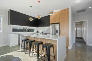 una cucina con sgabelli da bar e armadi in bianco e nero di Stylish Serenity - Martinborough Holiday Home a Martinborough