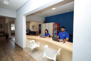 a man and woman sitting at a counter with a laptop at Pousada Acqua Azul in Bertioga