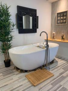 La salle de bains est pourvue d'une grande baignoire blanche et d'un miroir. dans l'établissement La Bohème - Bed & Breakfast, à Bromont