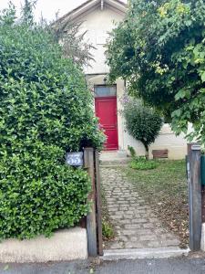 una casa con una puerta roja y algunos arbustos en La maison de Nita - chambres d'hôtes en Bergerac