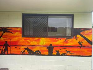 ein Gemälde an der Seite einer Wand mit einem Fenster in der Unterkunft The Sundown Lodges Rarotonga in Arorangi