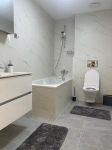 a bathroom with a tub and a toilet and a sink at C-entral Apartments Bucharest with Private Parking in Bucharest