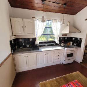 cocina con armarios blancos, fregadero y ventana en Ensueño casa de isla en Tigre