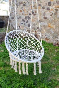 a white basket swing hanging from a stone wall at Villa Aubépine in La Bourboule