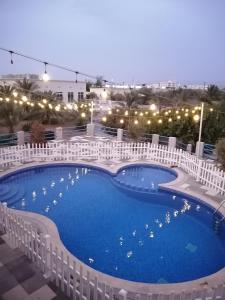 una gran piscina rodeada de vallas blancas. en مزرعة واستراحة المنامة, 