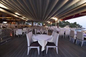 a restaurant with white tables and chairs on a deck at Epavlis Beach Resort in Porto Heli