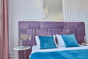 a bed with a purple head board with blue pillows at Elegant Lux Apartment in central square in Mukacheve