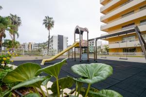 un parque infantil frente a un edificio con tobogán en By the Sea II - calmo com piscina e vista mar., en Funchal