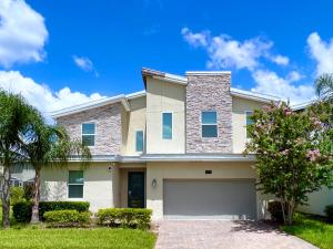 a house with a driveway and a tree at Beautiful 8 Bed Home in Champions Gate-303OC in Kissimmee