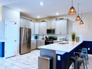 a kitchen with white cabinets and a kitchen island with stools at Beautiful 8 Bed Home in Champions Gate-303OC in Kissimmee