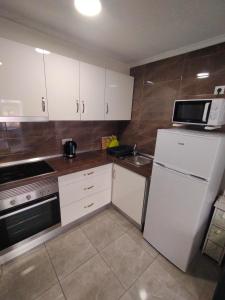 a kitchen with a white refrigerator and a microwave at Apartament Goleta in Torrevieja