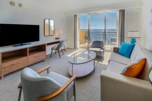 a living room with a tv and a couch and chairs at The Atlantic Hotel & Spa in Fort Lauderdale