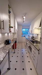a large white kitchen with a black and white tiled floor at Escape To The City in London