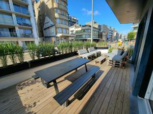 una terrazza in legno con tavolo da picnic e sedie in un edificio di Family apartment on the ground floor with terrace - Panne A Côte a De Panne