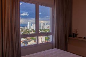 1 dormitorio con ventana grande con vistas a la ciudad en Blend Smart Style Estúdios Luxuosos e Decorados, en Goiânia