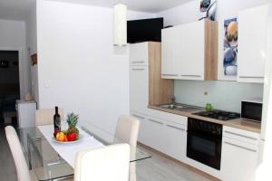 una cocina con armarios blancos y una mesa con un bol de fruta en Apartman Orange s pogledom na more i 50m od plaže, en Vodice