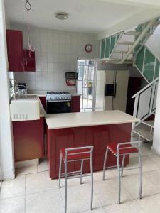 une cuisine avec des placards rouges et un comptoir avec deux tabourets dans l'établissement A big house for a big time., à La Joya