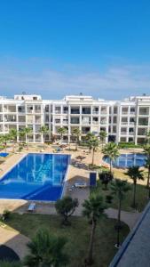 a large apartment building with a pool and palm trees at relax à Costa Beach in Bouznika