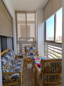 a balcony with chairs and tables and windows at relax à Costa Beach in Bouznika