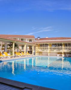 a large swimming pool with chairs and a building at Hotel et Spa Les Cleunes Oléron in Saint-Trojan-les-Bains