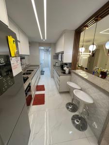 een keuken met witte kasten en krukken. bij Apartamento em Manaus in Manaus