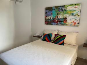 a white bed with two pillows and a painting on the wall at Casa hotel Mateguadua in Apartadó