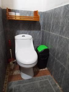 a bathroom with a toilet and a green trash can at Casa Bambu in Pavones