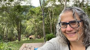 a woman wearing glasses sitting on a wooden bench at Vila Drávida in Iporanga