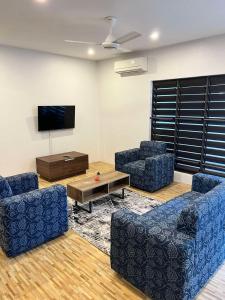 a living room with two blue chairs and a tv at Garden Apartments in Nadi