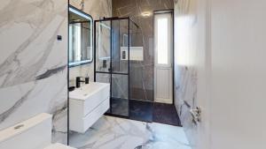 a white bathroom with a shower and a sink at Serenity Retreats VRT in Sibiu +6 photos